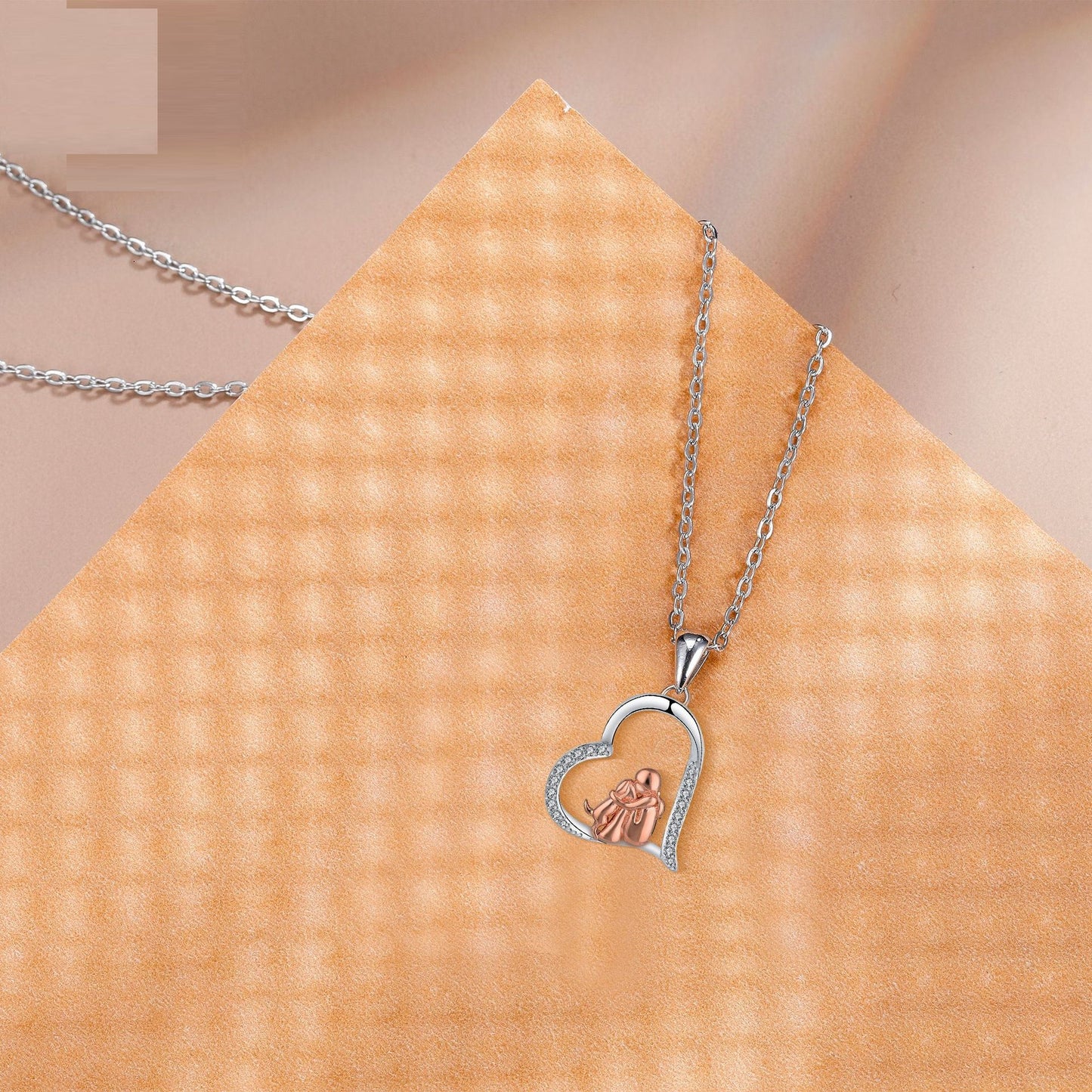 Heart-shaped pendant necklace on a textured beige surface