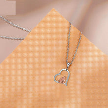 Heart-shaped pendant necklace on a textured beige surface