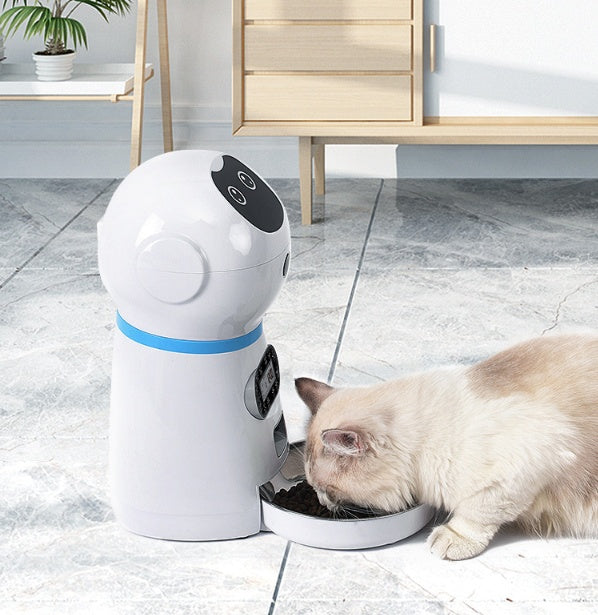 Pet robot feeder dispensing food to a cat on a tiled floor.