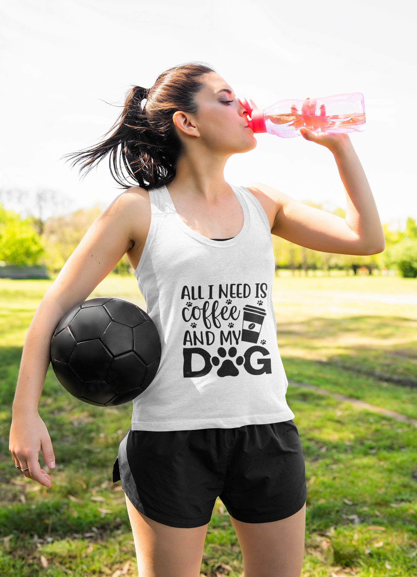 Coffee Dog Lover's Racerback Tank worn by woman holding soccer ball and drinking water outdoors