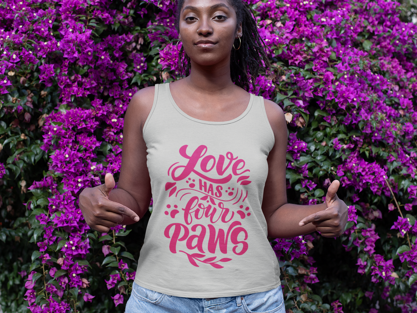 Gray Printify tank top with pink Love Has Four Paws design worn by woman standing in front of purple flowers
