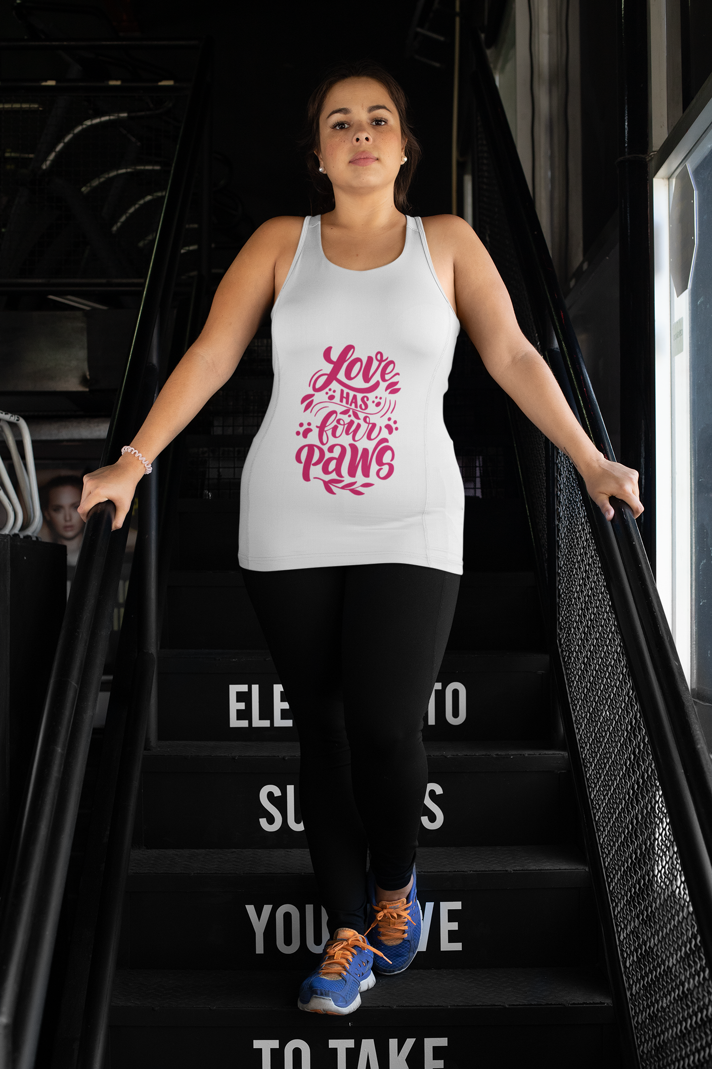 White tank top with pink Love Has Four Paws design worn by woman on stairs