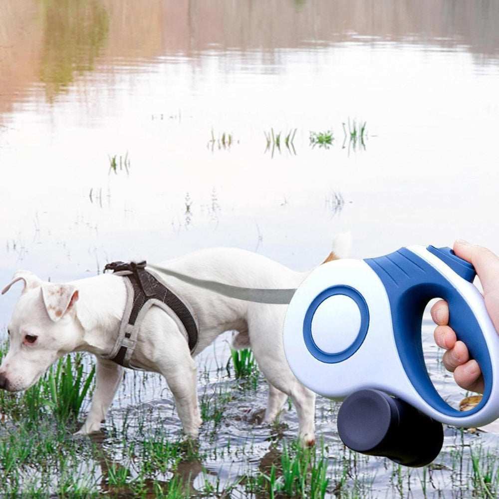 Purrfect Pet Haven Retractable Dog Leash blue and white handle held as a white dog in a harness explores shallow pond grass