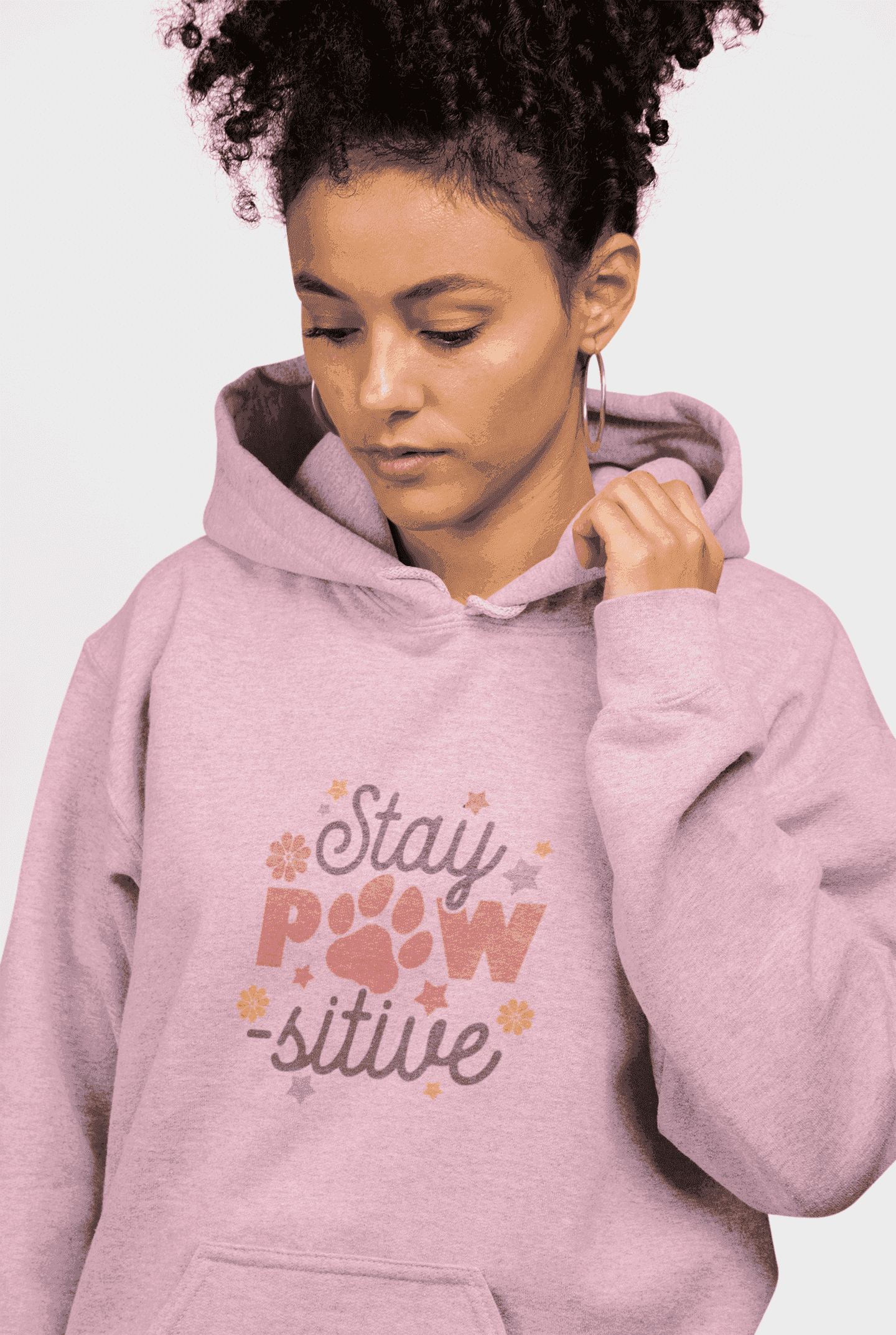 Stay Pawsitive Unisex Hoodie worn by woman model in pink with paw print graphic and kangaroo pocket