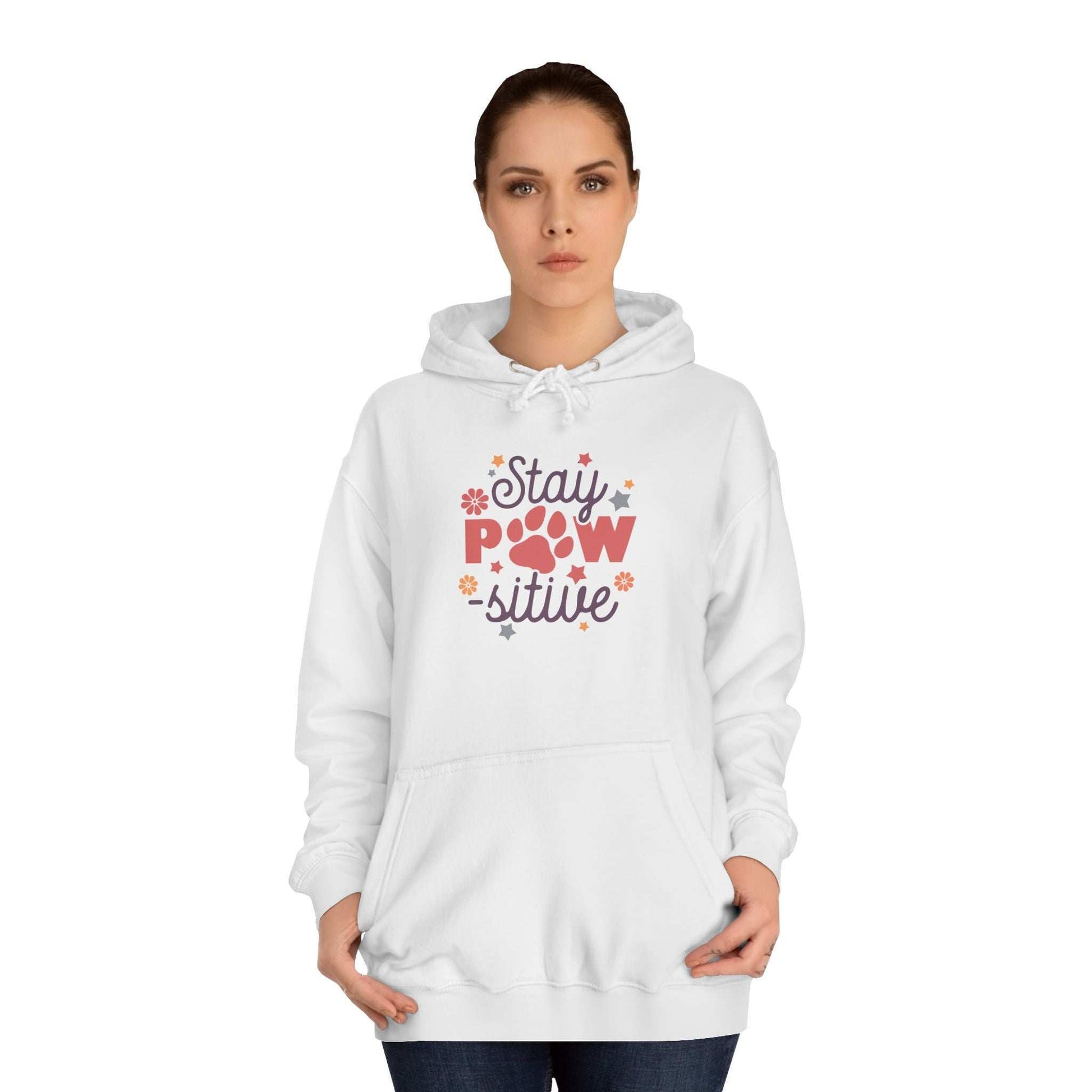 Woman wearing white Stay Pawsitive Unisex Hoodie with paw print and floral graphic front pocket hood casual pet lover gift