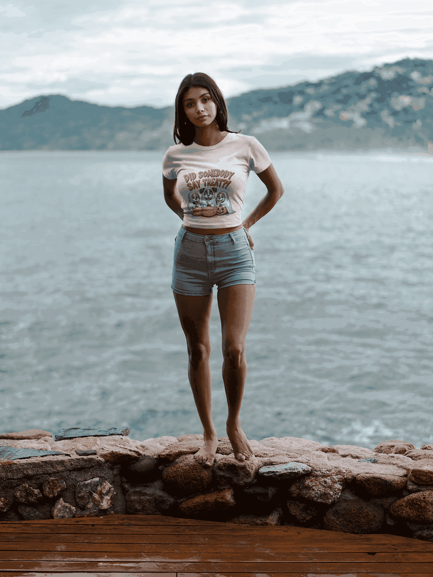 Spooky Halloween Dog Tee on woman model standing barefoot on rocky shore wearing cropped tee and denim shorts