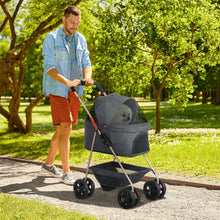 Man pushing a gray pet stroller with a dog in it through a park.