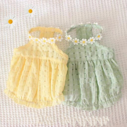 Two baby rompers, one yellow and one green, with floral headbands on a textured white background.