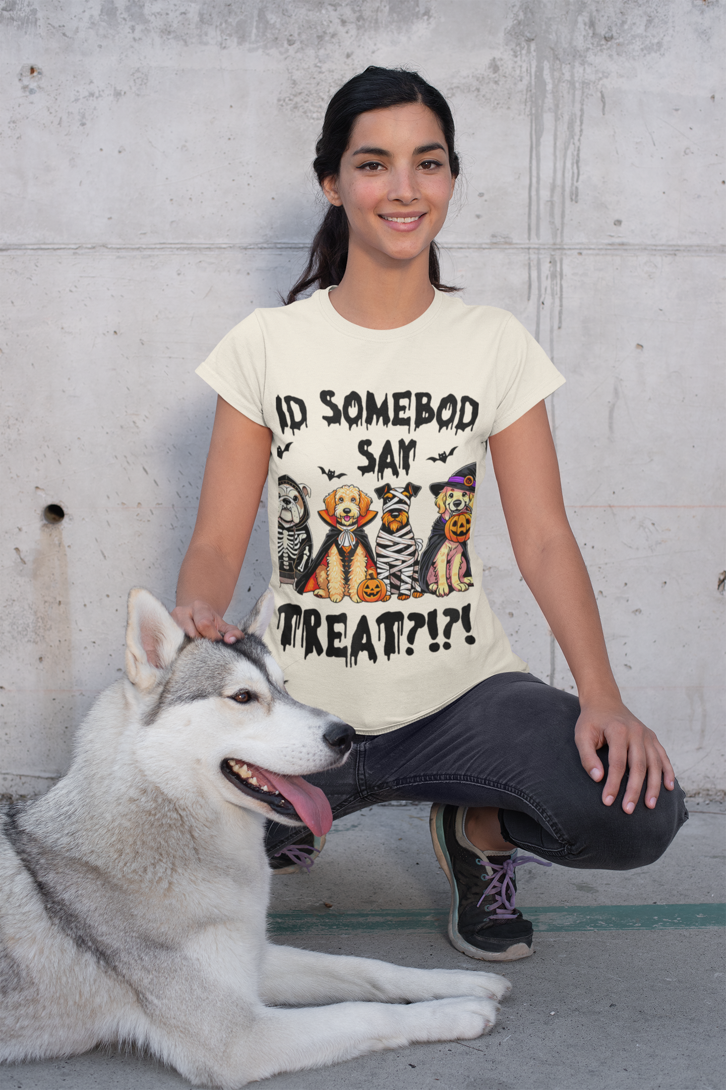 Young woman kneeling by a husky wearing a Printify Heavy Cotton T-Shirt with Halloween dog graphic Did somebody say treat