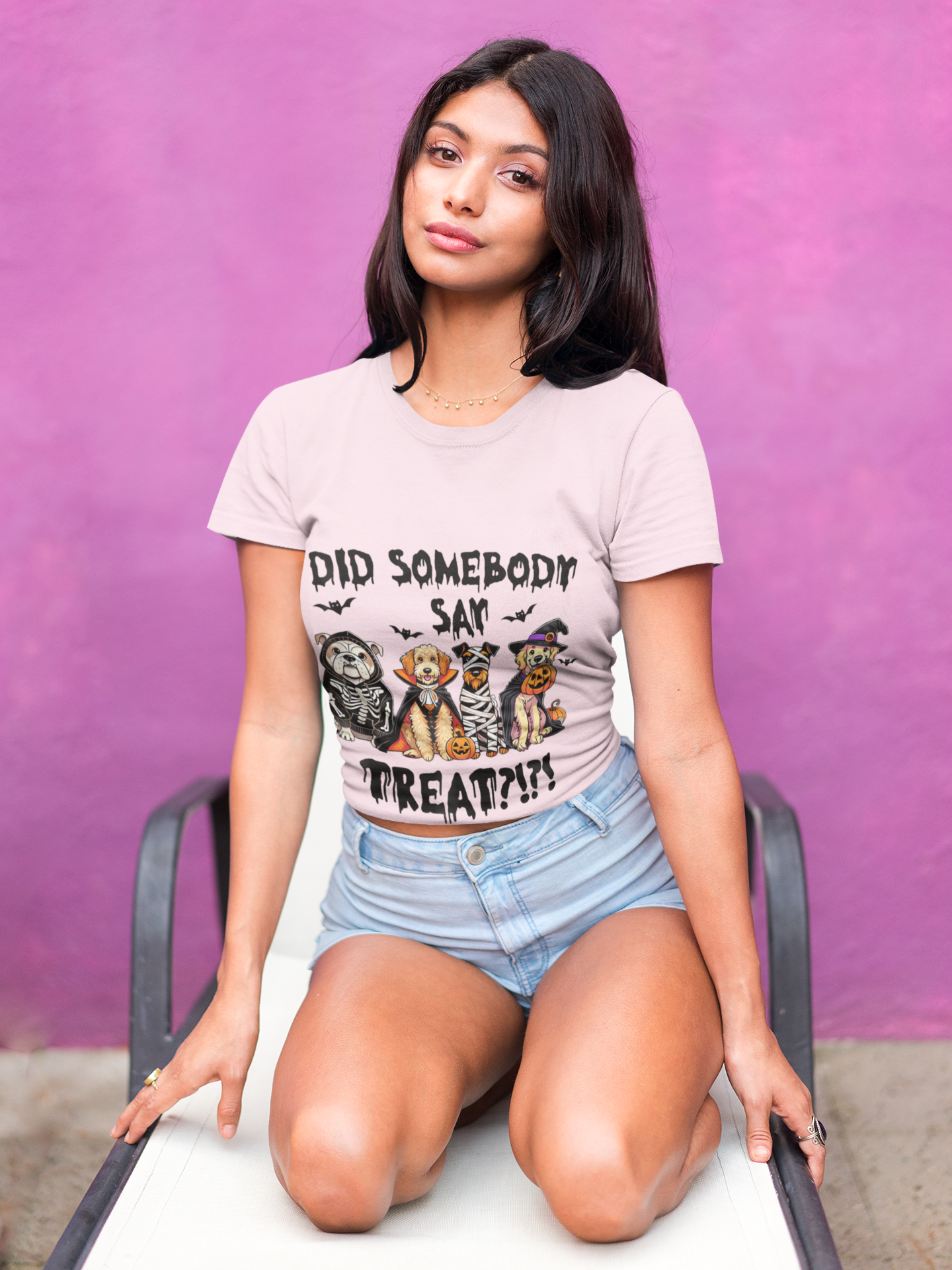 Woman kneeling on lounge chair wearing Heavy Cotton T-Shirt pale pink with Halloween dog costume graphic