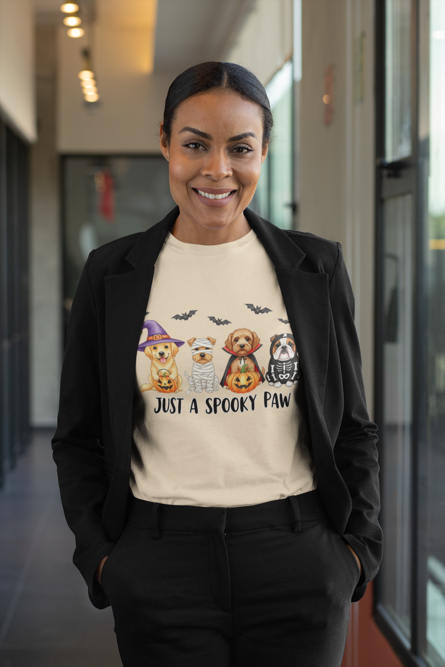 Smiling woman wearing a Printify Spooky Pet Shirt beige tee featuring three dogs in Halloween costumes