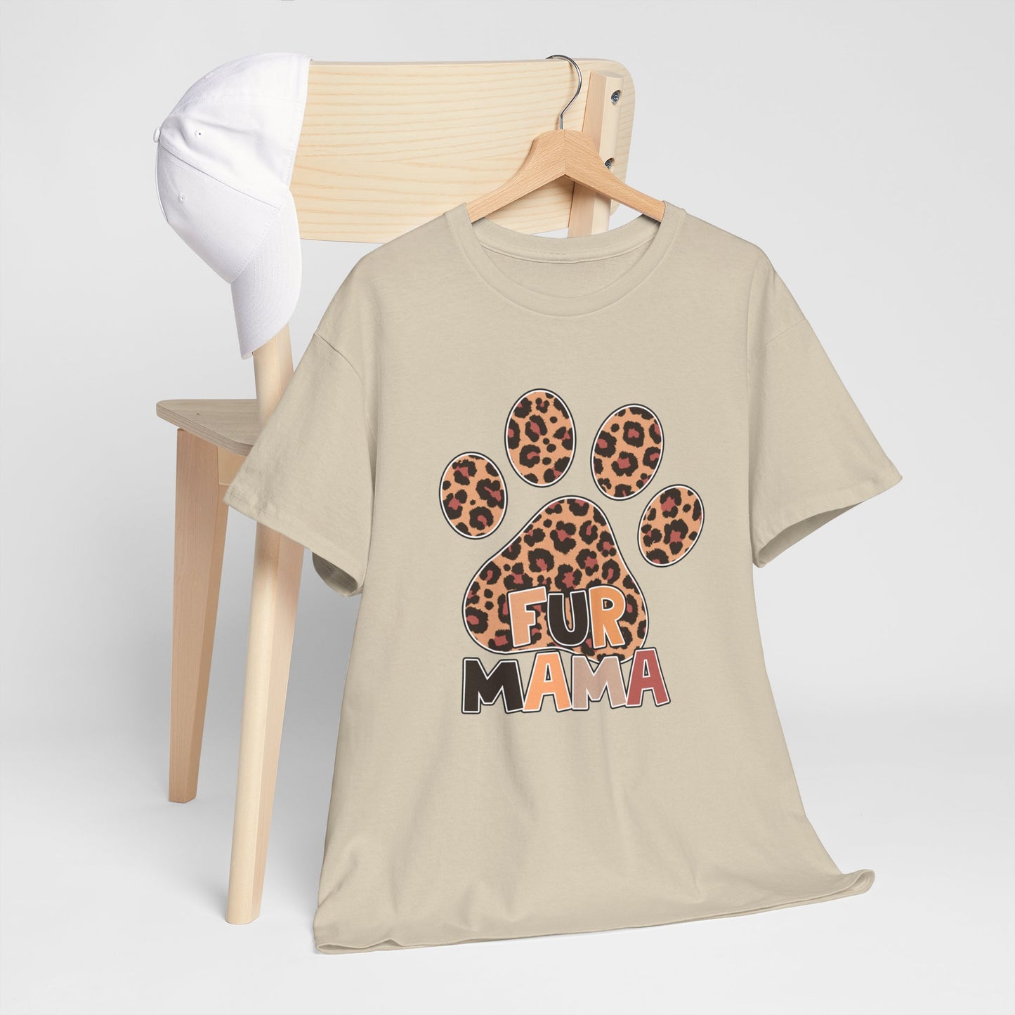 Printify Heavy Cotton T-Shirt beige tee with leopard paw print and FUR MAMA text on hanger by chair
