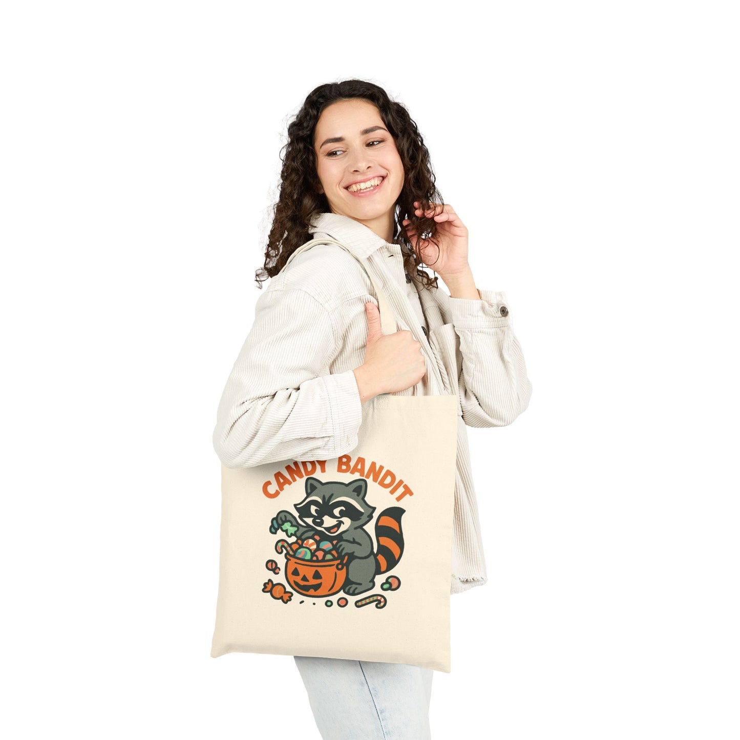 Printify Canvas Tote Bag with Candy Bandit raccoon Halloween pumpkin candy design on beige tote carried by smiling model