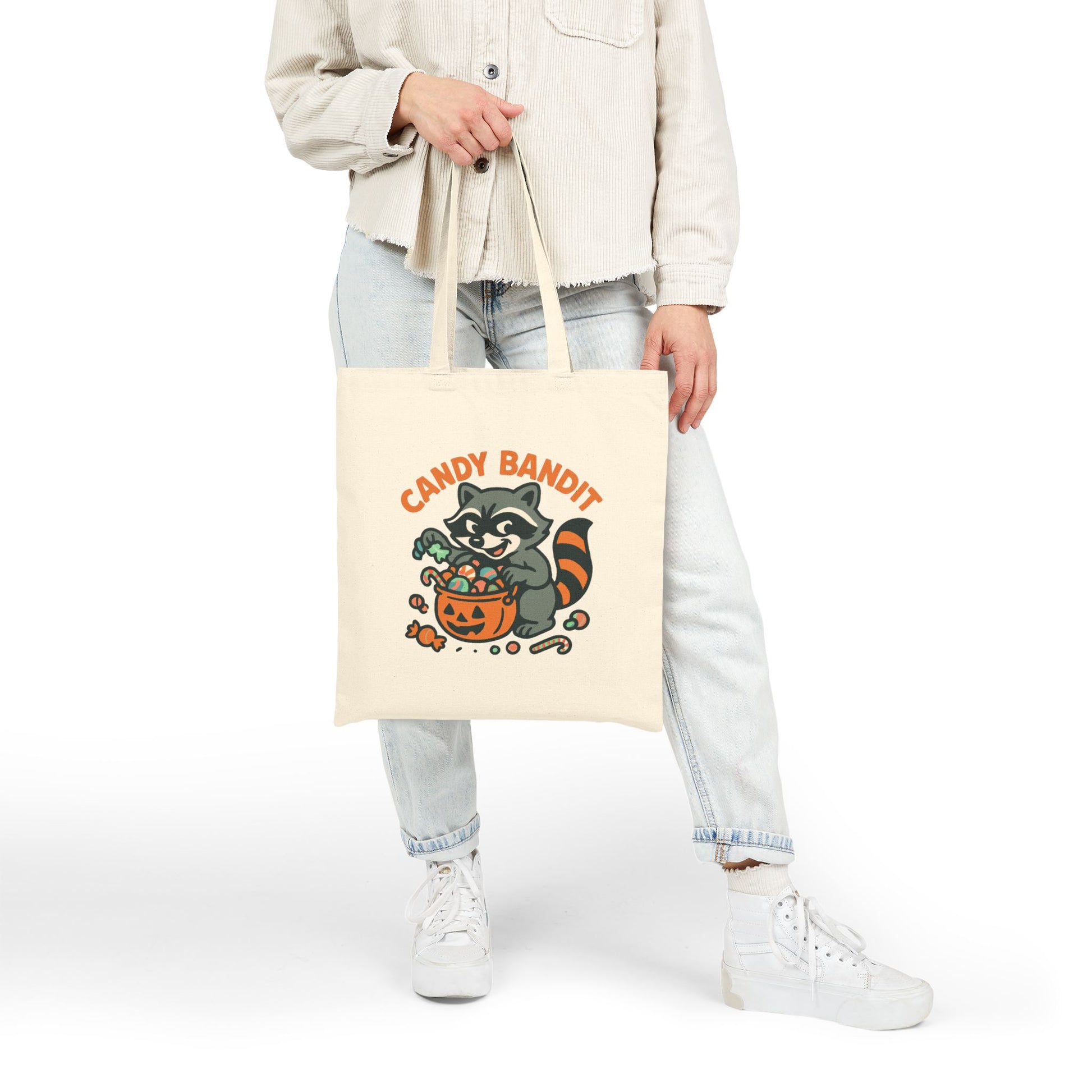 Printify Canvas Tote Bag off white with Candy Bandit raccoon Halloween candy pumpkin print held by model