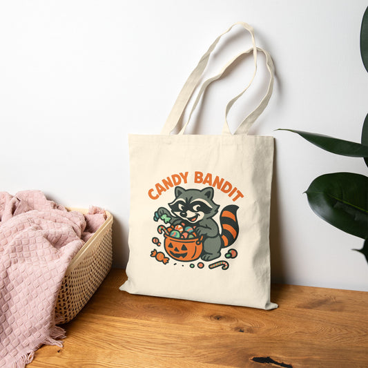 Printify Canvas Tote Bag featuring Candy Bandit raccoon with pumpkin candy bucket on natural canvas tote