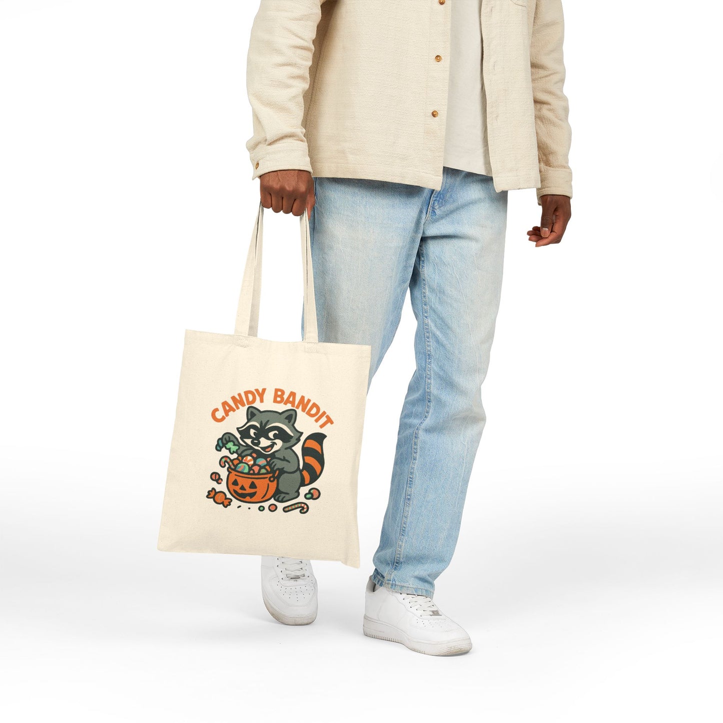 Canvas Tote Bag with Candy Bandit raccoon Halloween print held by person wearing jeans and white sneakers