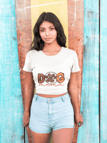 Model wearing Printify Dog Mama Tee white cropped t shirt with paw print design and denim shorts