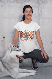 Woman kneeling with husky pet wearing white Dog Mama Tee featuring paw print design outdoors