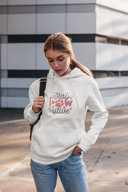 Young woman wearing Printify white Stay Pawsitive Unisex Hoodie with paw print design and kangaroo pocket