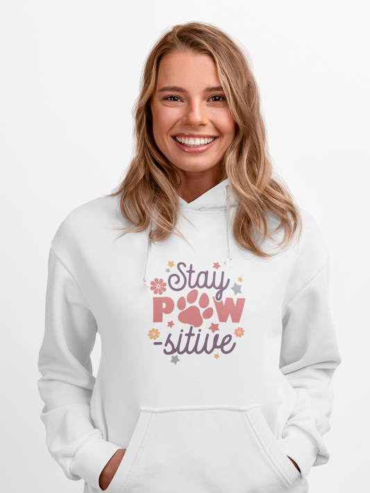 Smiling woman wearing white Stay Pawsitive Unisex Hoodie with paw print design and kangaroo pocket