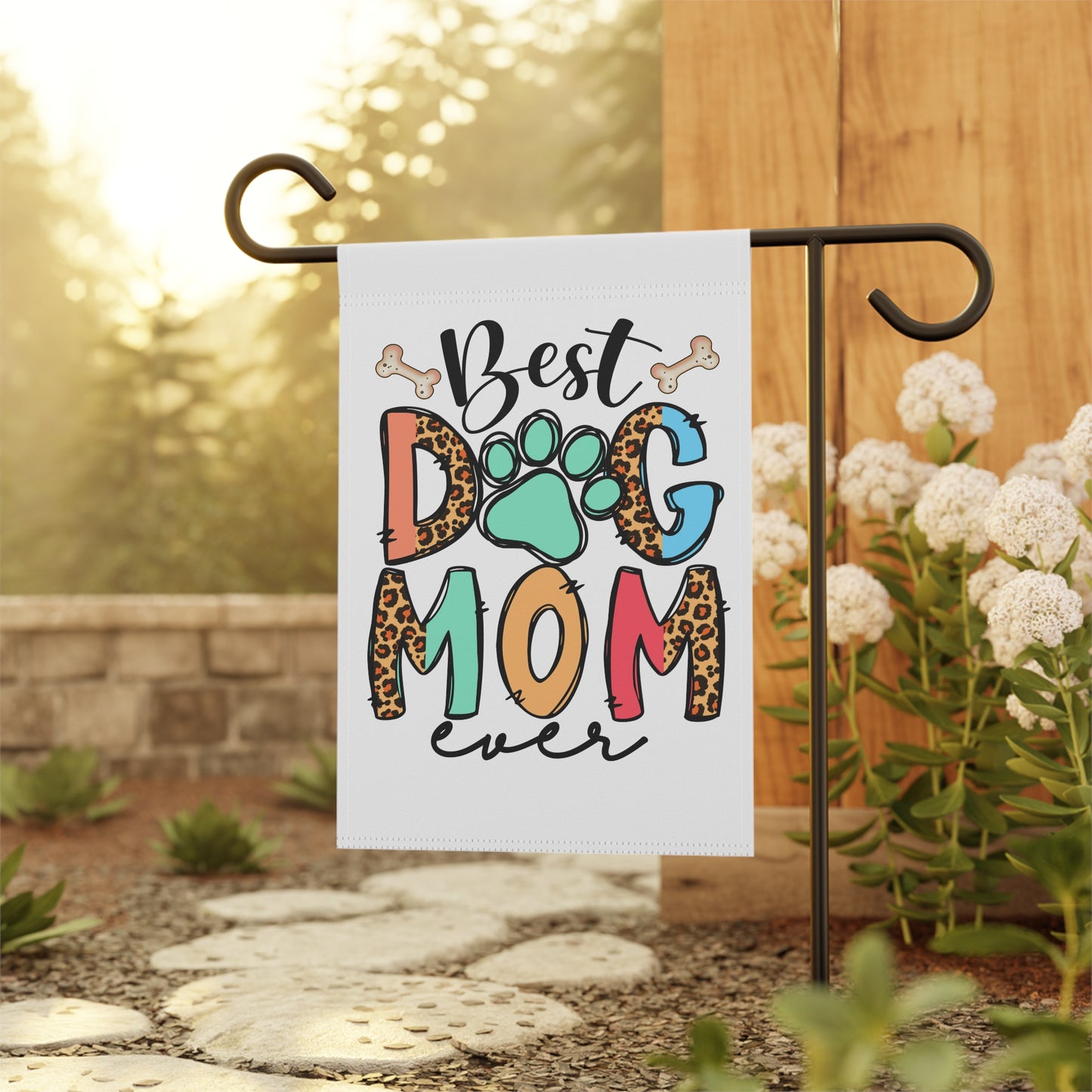 Dog Mom Garden Flag on a metal pole in a sunny garden featuring Best Dog Mom ever design with paw print and leopard print letters