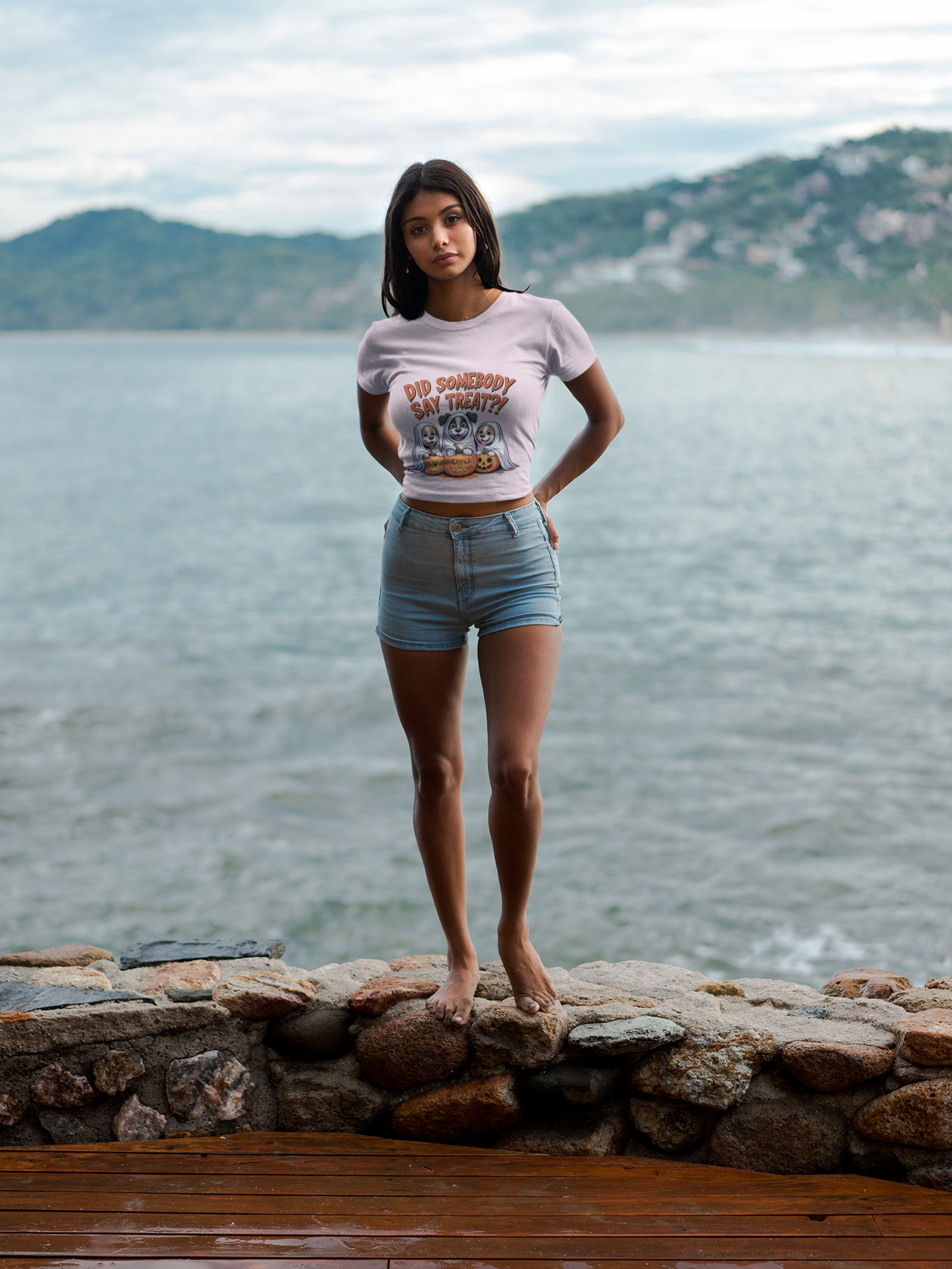 Spooky Halloween Dog Tee on woman model standing barefoot on rocky shore wearing cropped tee and denim shorts