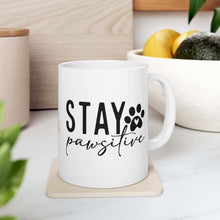 White ceramic Stay Pawsitive Mug with black text and paw print design on coaster