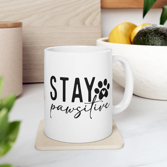 White ceramic Stay Pawsitive Mug with black text and paw print design on coaster