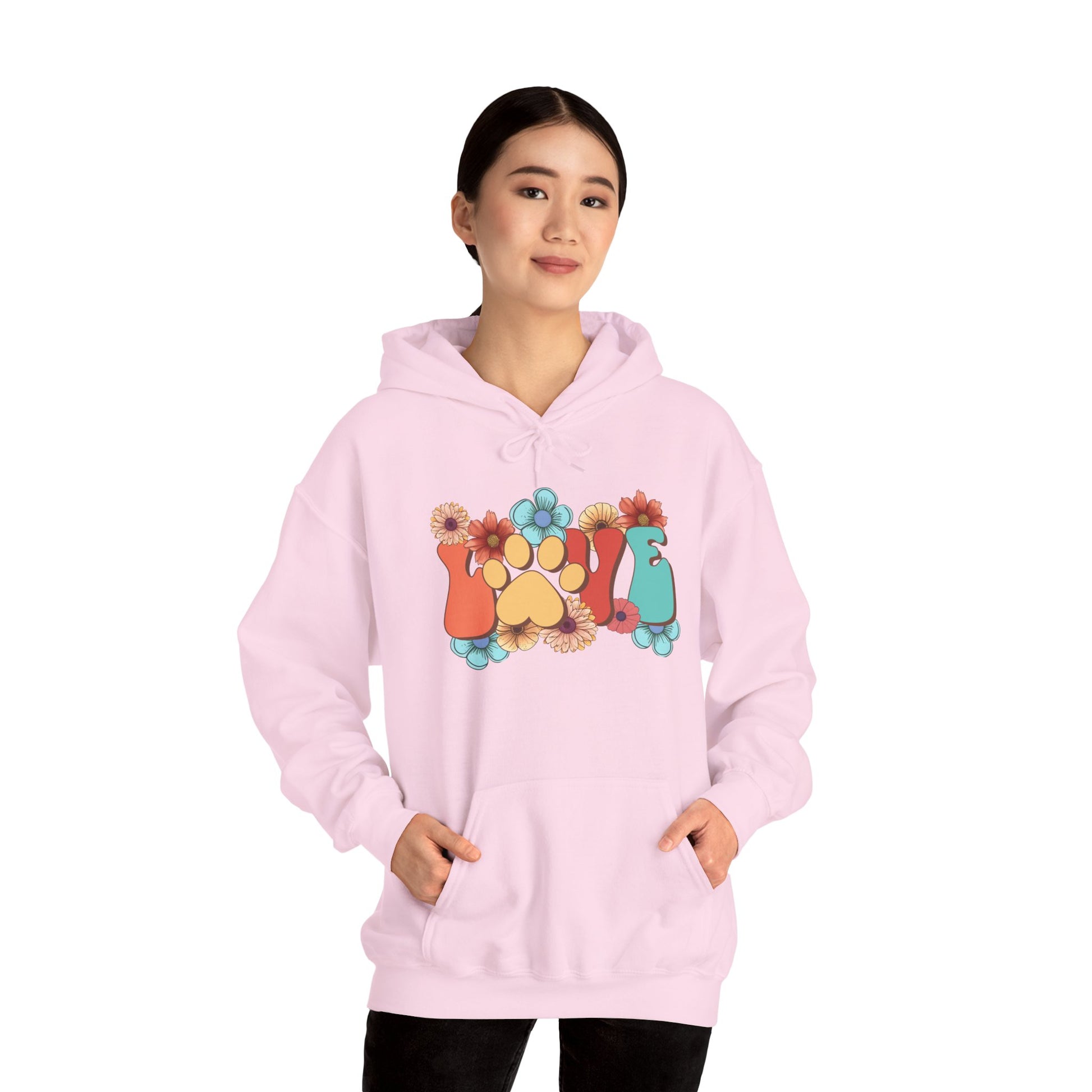 Printify light pink Animal Lover Hoodie worn by woman featuring colorful paw print and floral graphic